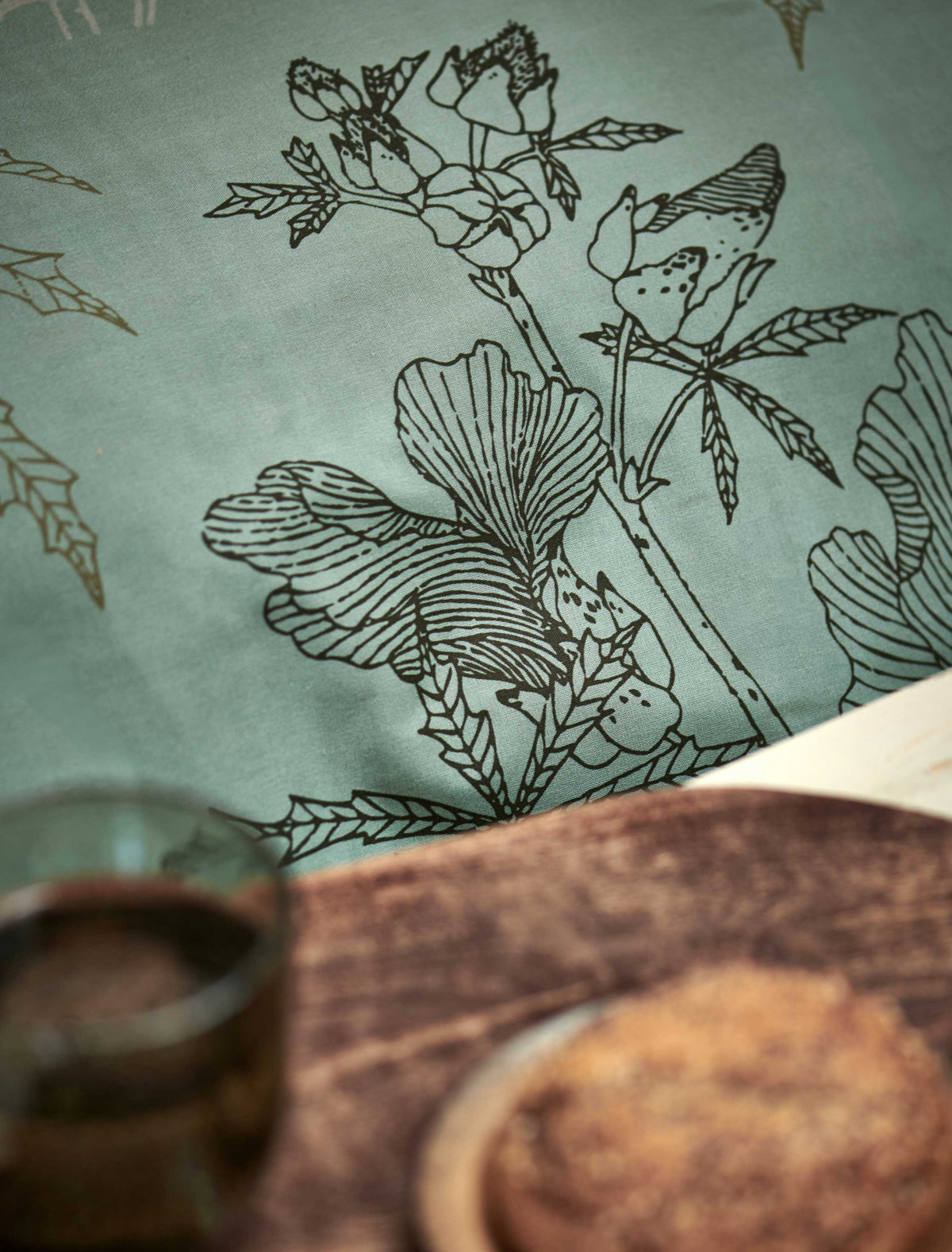 detail shot van een dekbedovertrek met een groene kleur met een zwarte opdruk van bloemen en bladeren
