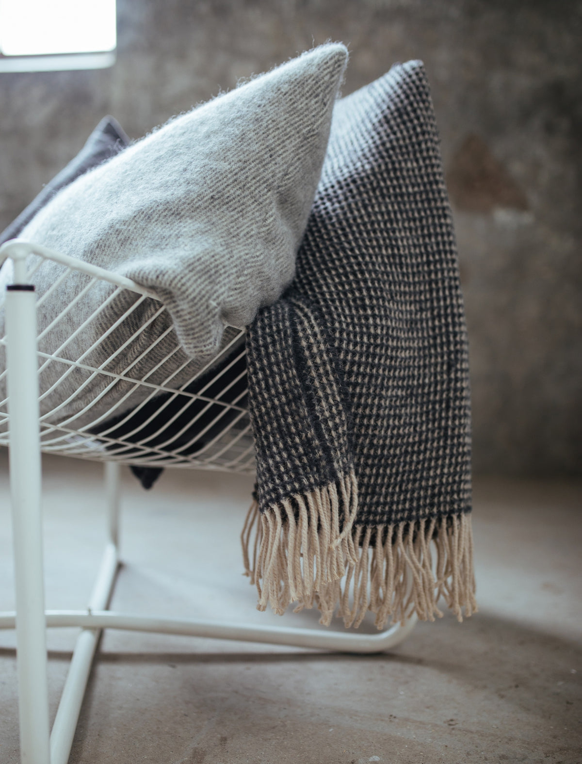 detail shot van een kussen van wol in en grijze kleur en een sprei