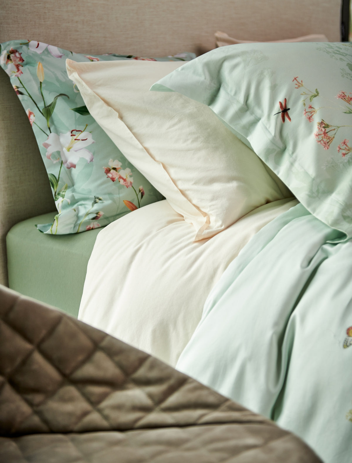 detail shot van een bed met kussens in beige en groene kleuren met bloemen