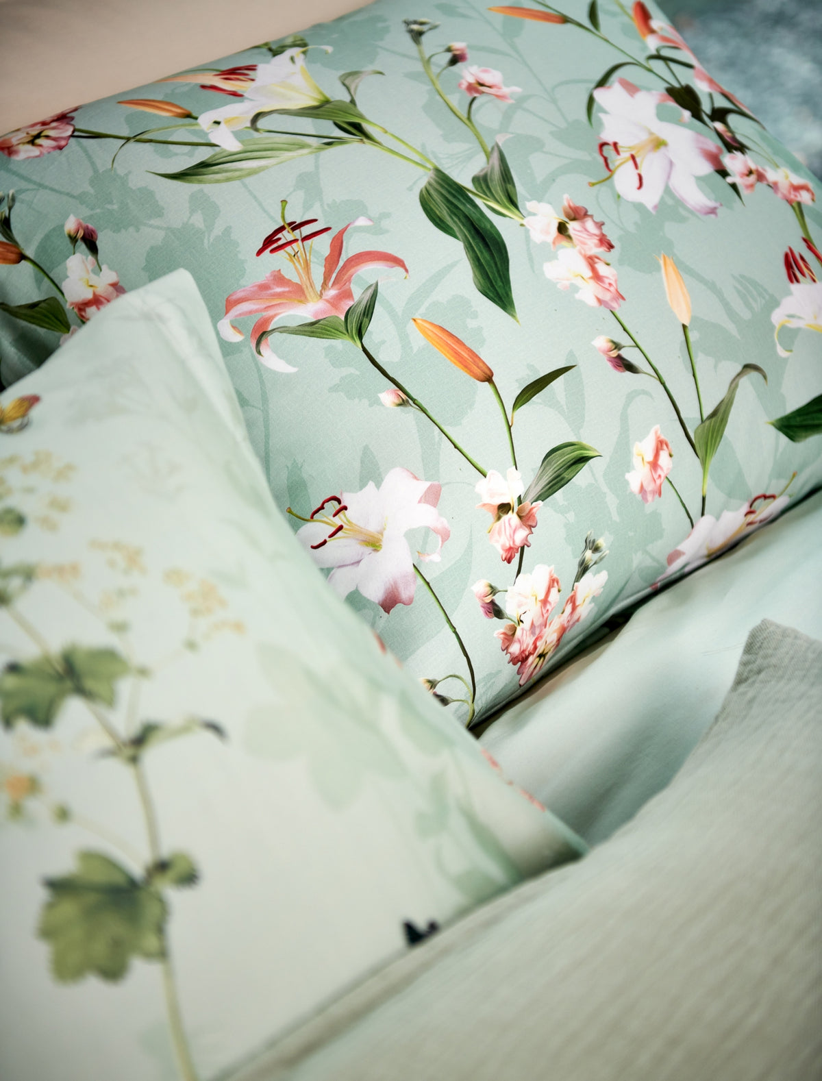 detail shot van een hoofdkussen in een groene kleur met bloemen in roze en oranje