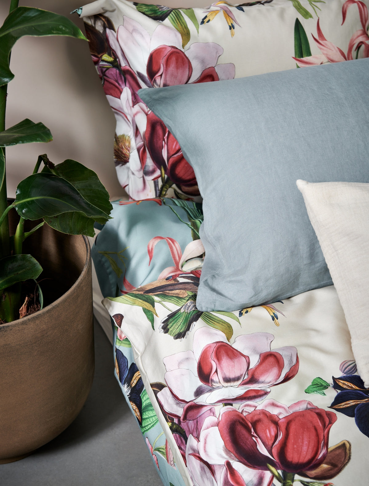 detail shot van een dekbedovertrek in een beige kleur met bloemen en een kussen in een blauwe kleur