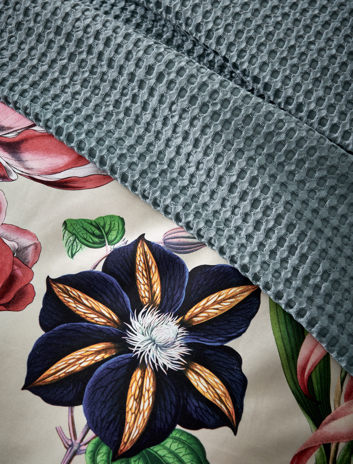 detail shot van een overtrek met bloemen en een beige ondergrondkleur en plaid in een blauwe kleur met waffle patroon