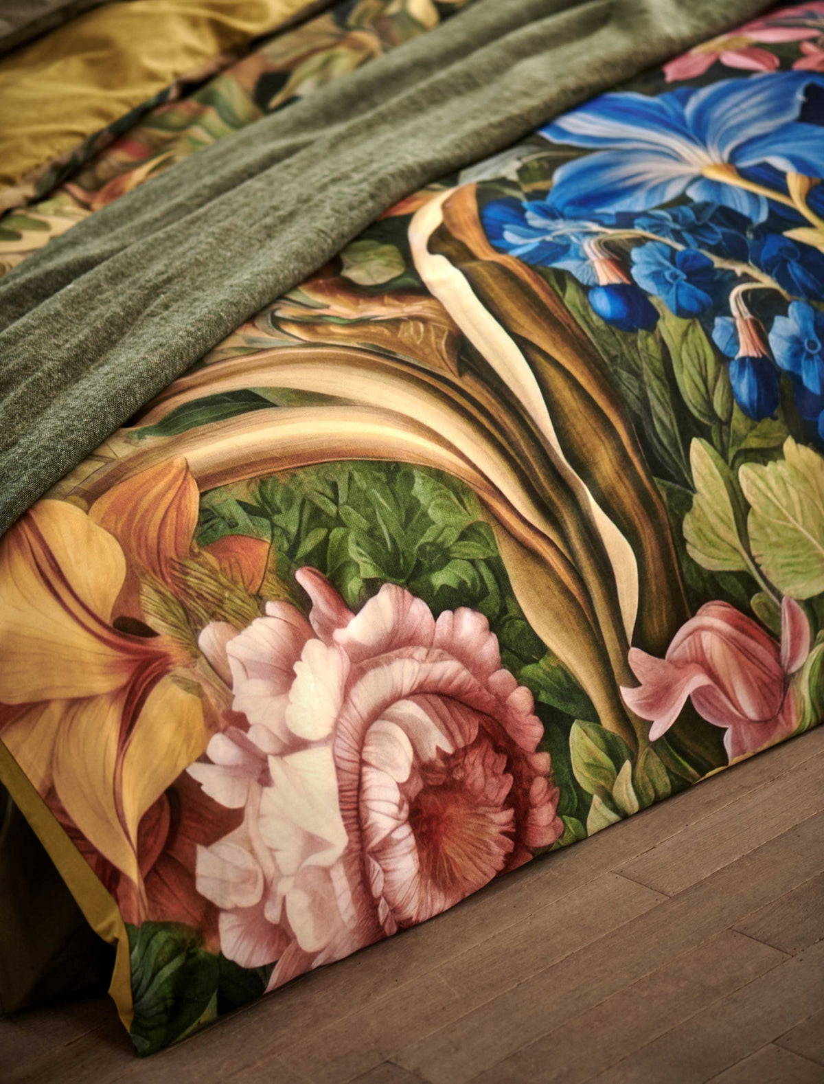 detail shot van een dekbedovertrek met bloemen in roze en blauwe kleur en een groen plaid