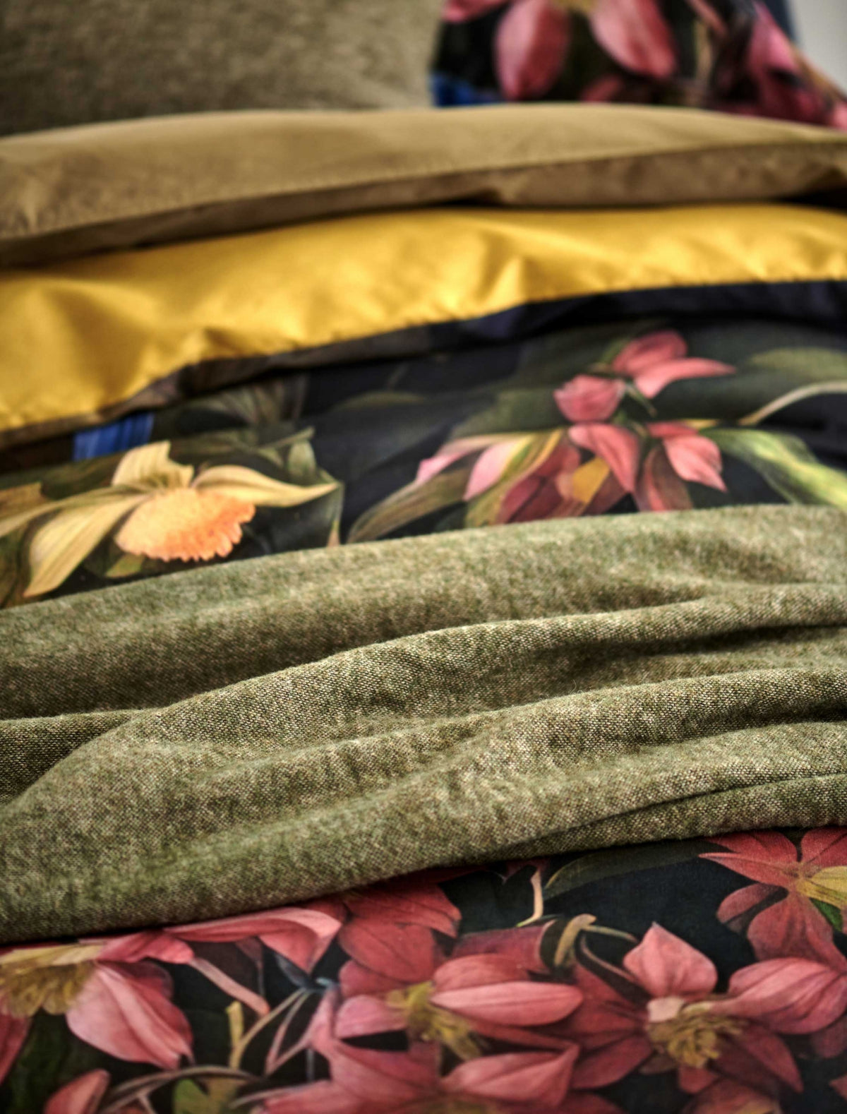 detail shot van een dekbedovertrek met roze bloemen en een groen wollen plaid