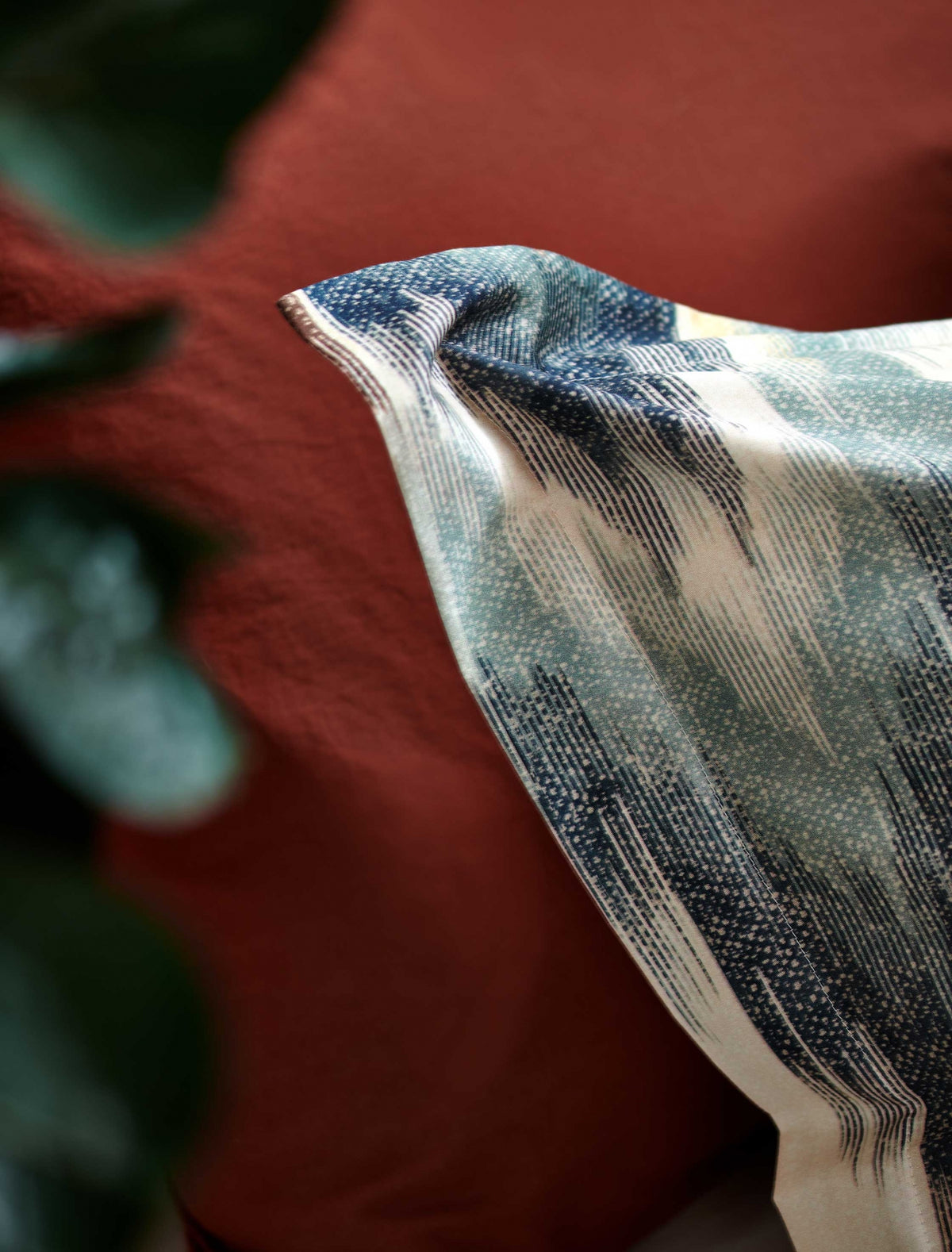 detail shot van een kussensloop in een bruin oranje kleur en een kussensloop met een blauwe print