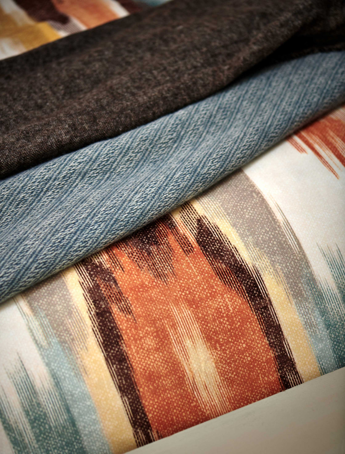 detail shot van een blauw sprei en een dekbedovertrek met print in oranje en blauwe kleuren