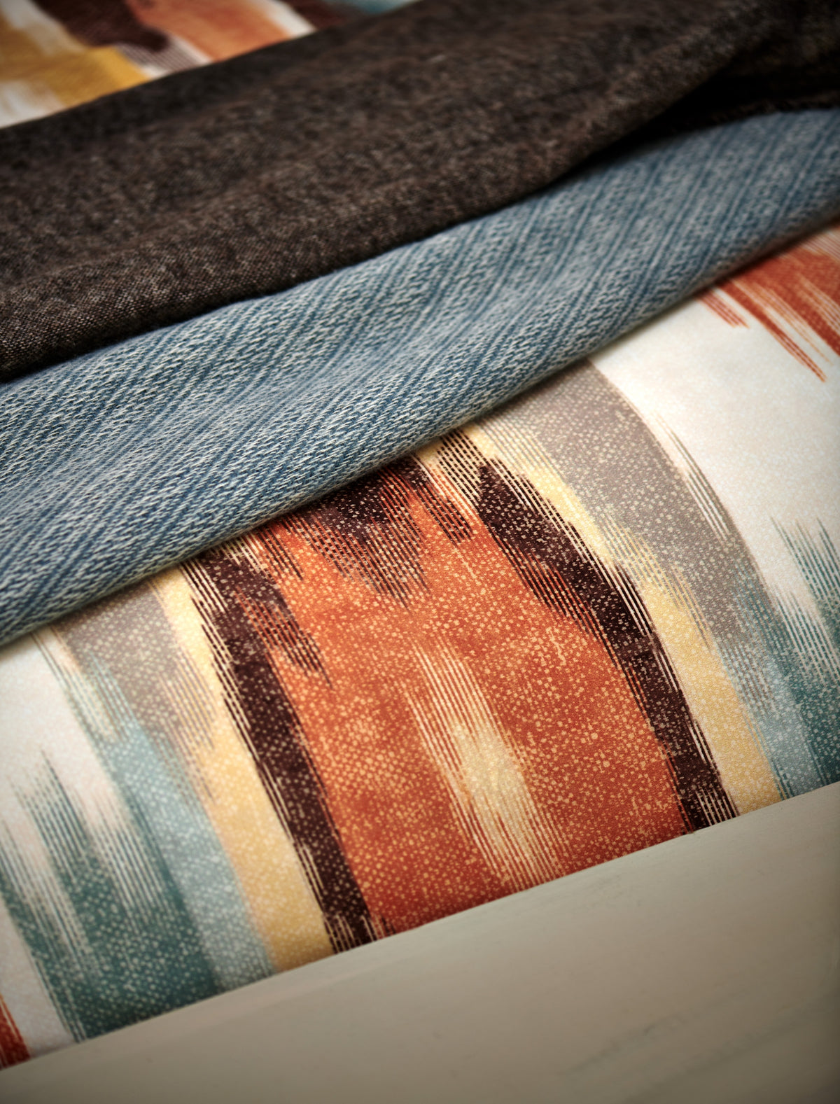 detail shot van een dekbedovertrek met print in een oranje kleur en een plaid van wolmix in een blauwe kleur