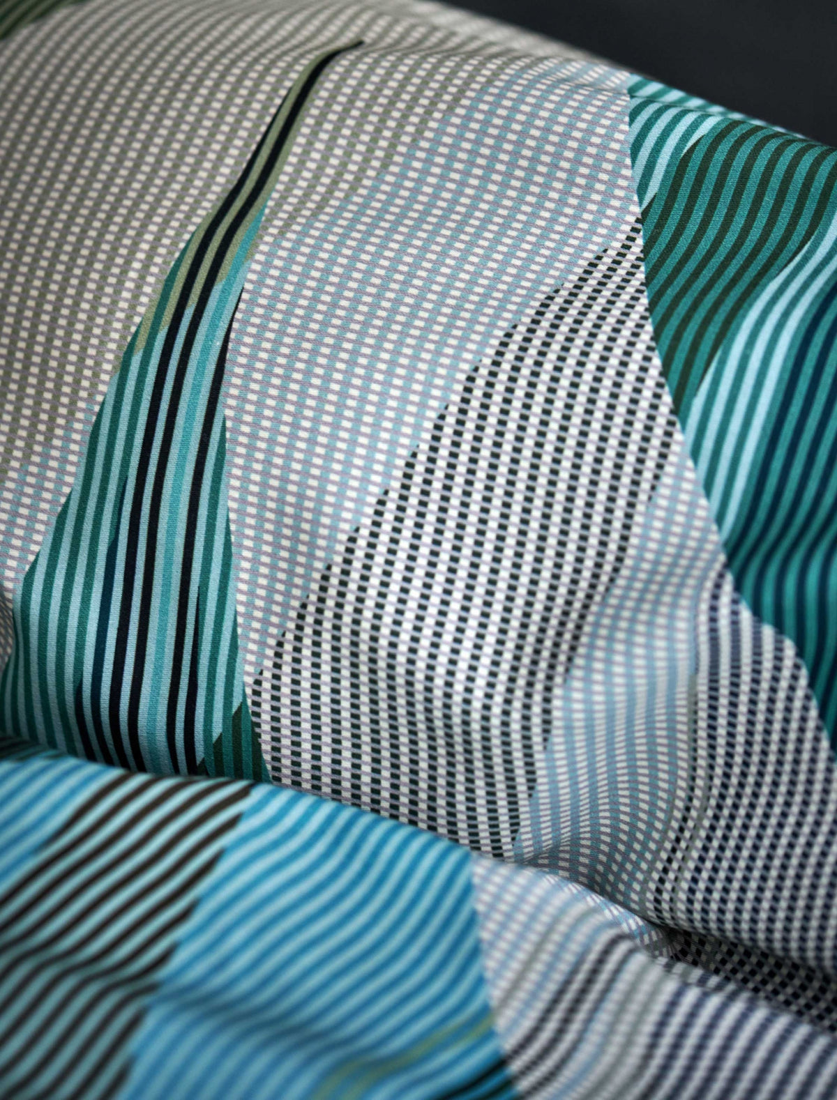 detail shot van een hoofdkussen in een print met groene, blauwe en beige kleuren