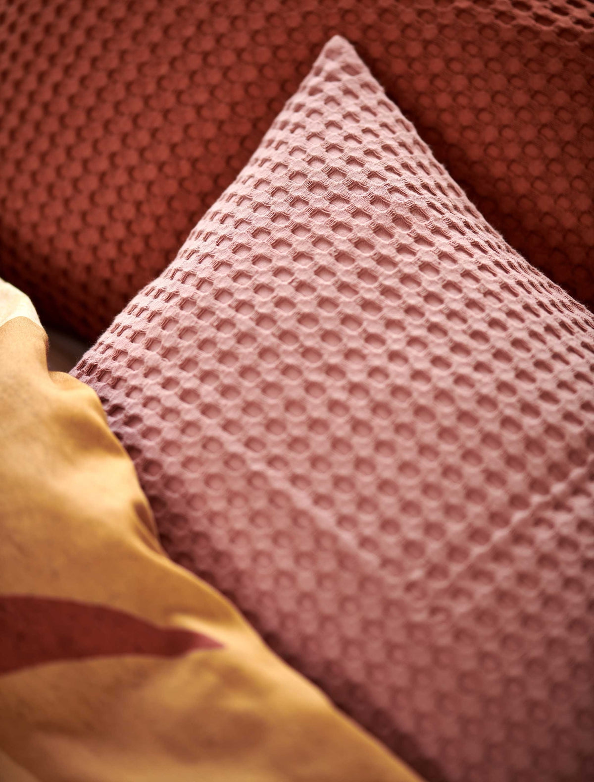 detail shot van een wafelstructuur sierkussen in een roze kleur