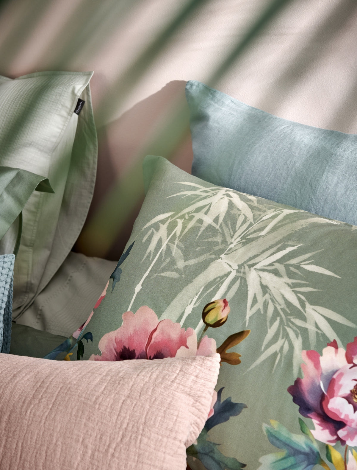 detail shot van een hoofdkussen in een groene kleur met roze bloemen en bamboe takken