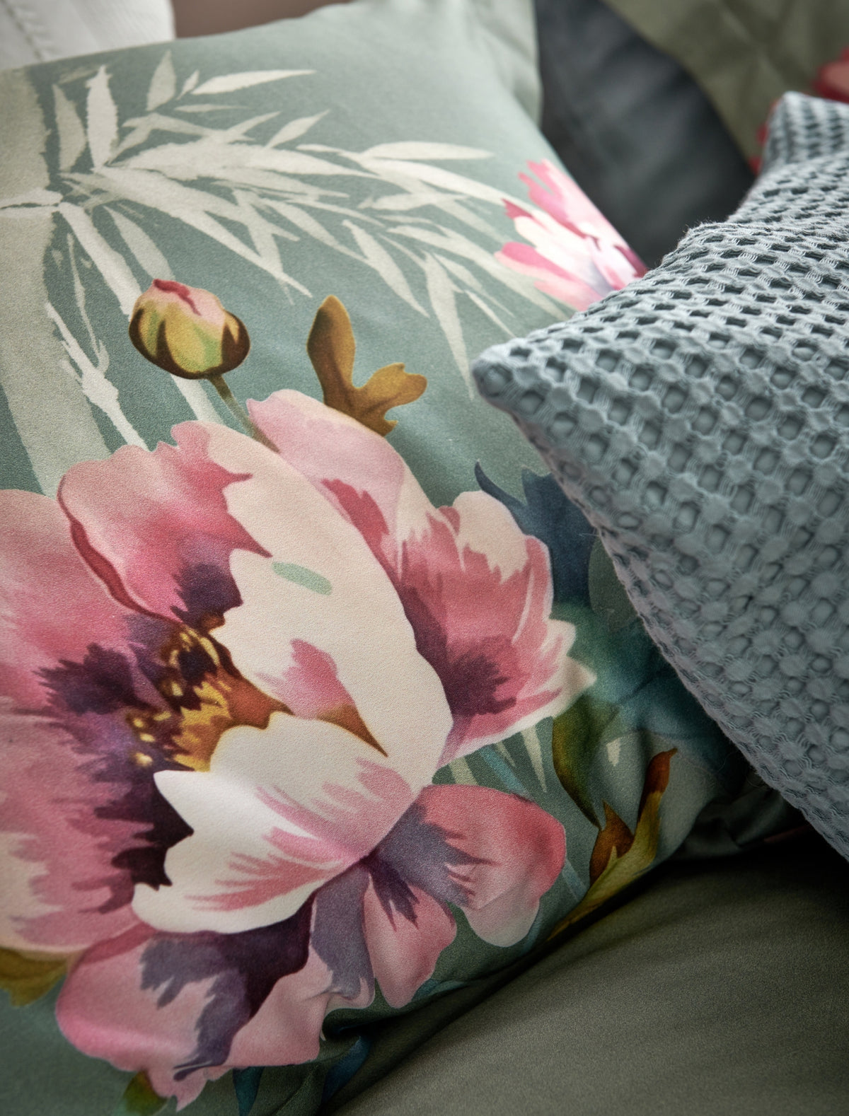 detail shot van een kussen met roze bloemen en bamboe takken op een groene achtergrond