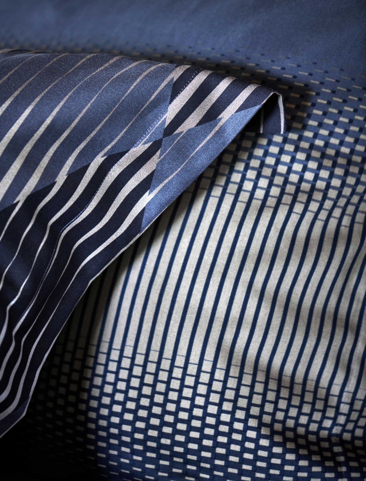 detail shot van een hoofdkussen met een grafische print in grijze en donkerblauwe kleuren