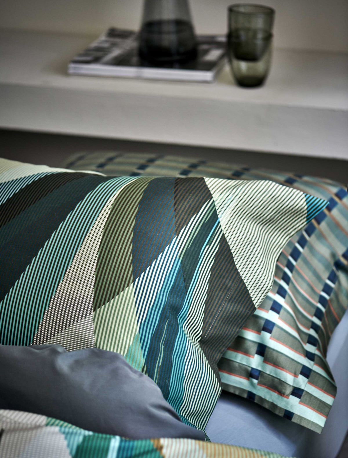 detail shot van een hoofdkussen met strepen en in groene, blauwe en beige kleuren