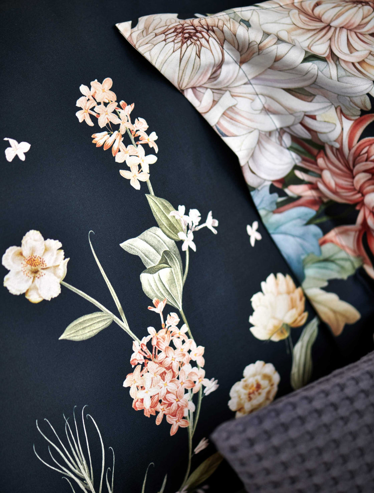 detail shot van een hoofdkussen in een donkerblauwe kleur met oranje en roze bloemen