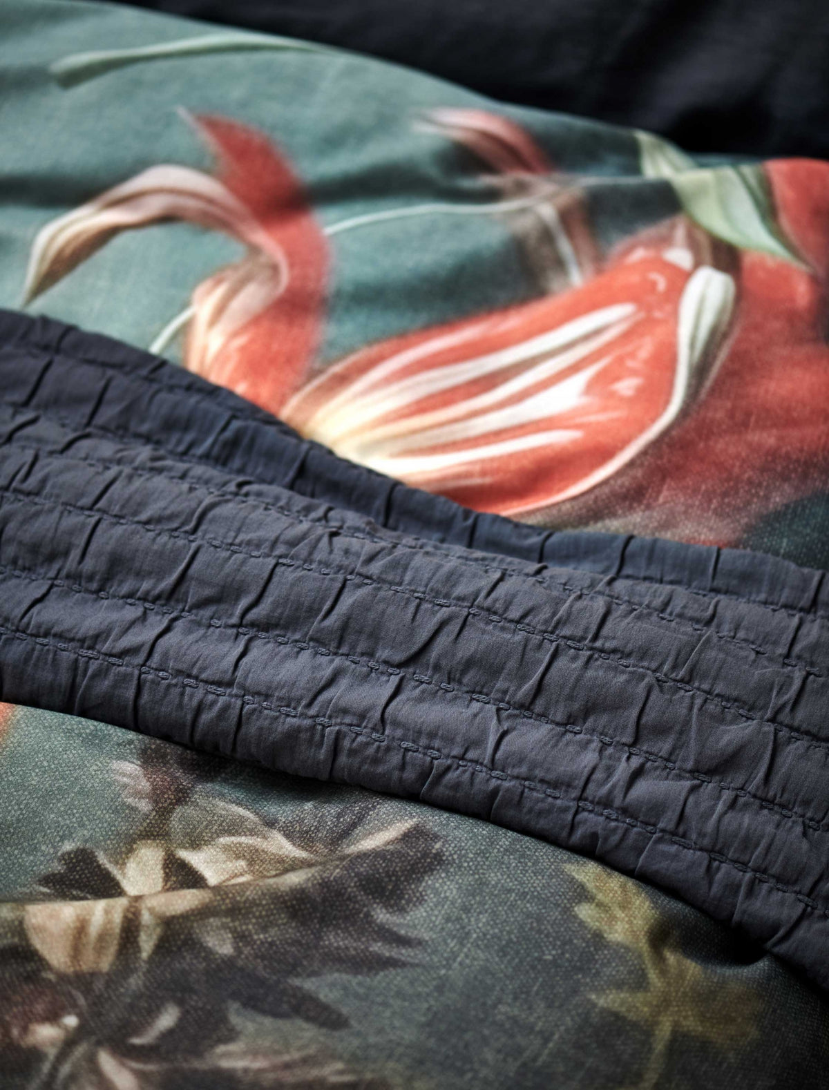 detail shot van een sprei in een donkerblauwe kleur en een dekbedovertrek met bloemenprint