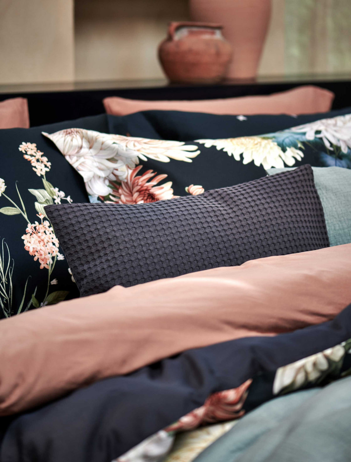 detail shot van een bed met daarop een sierkussen in een blauwe kleur en een dekbedovertrek in een blauwe kleur met bloemen