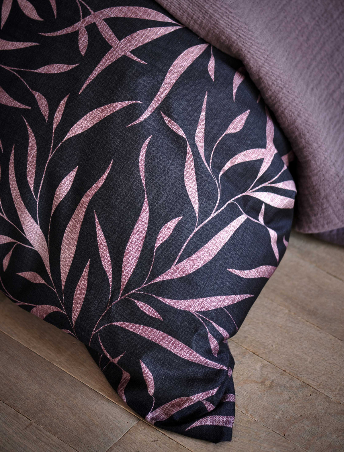 detail shot van een dekbedovertrek met bladeren in paarse en roze kleuren