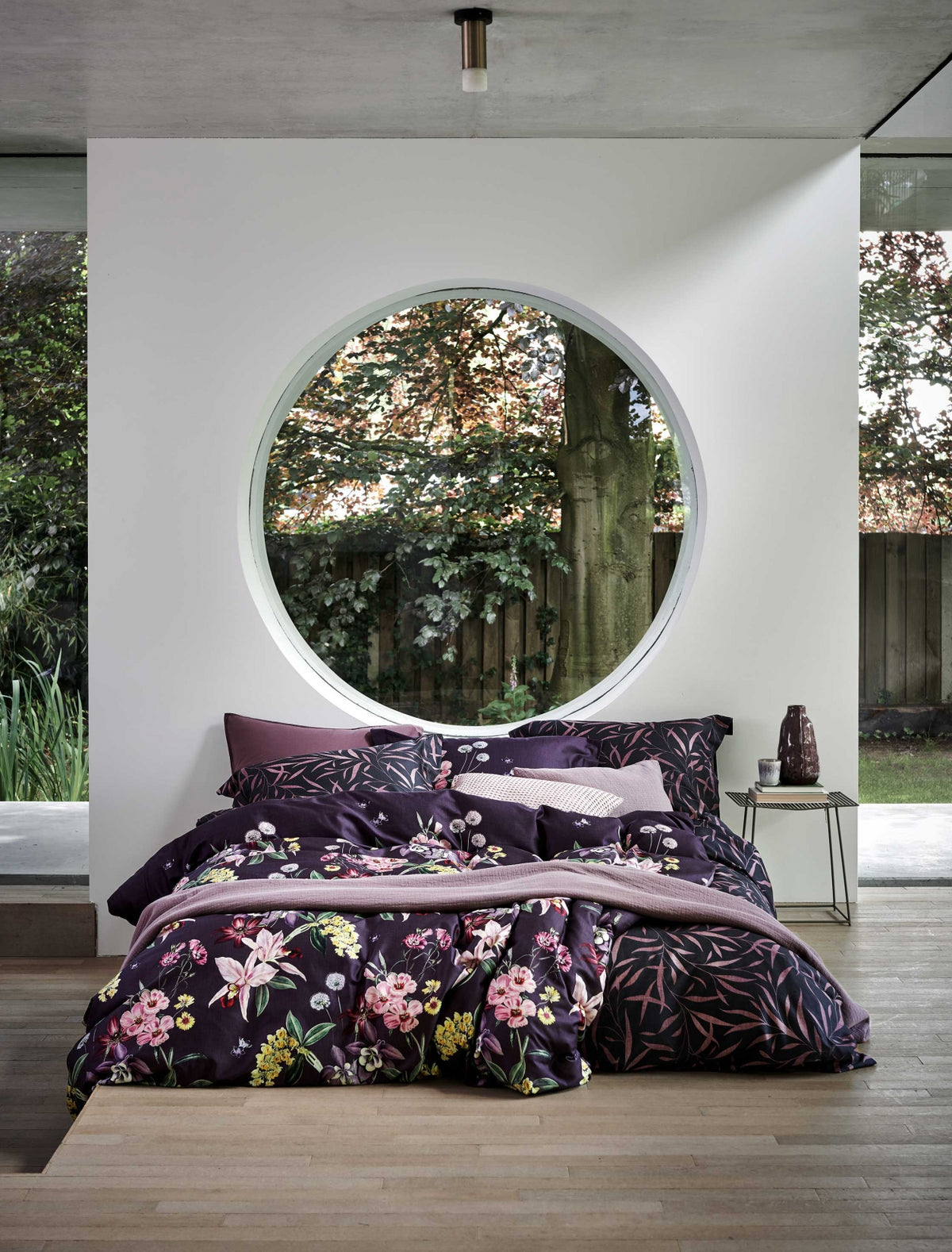 Een bed met een dekbedovertrek met bloemen en bladeren in paarse kleuren