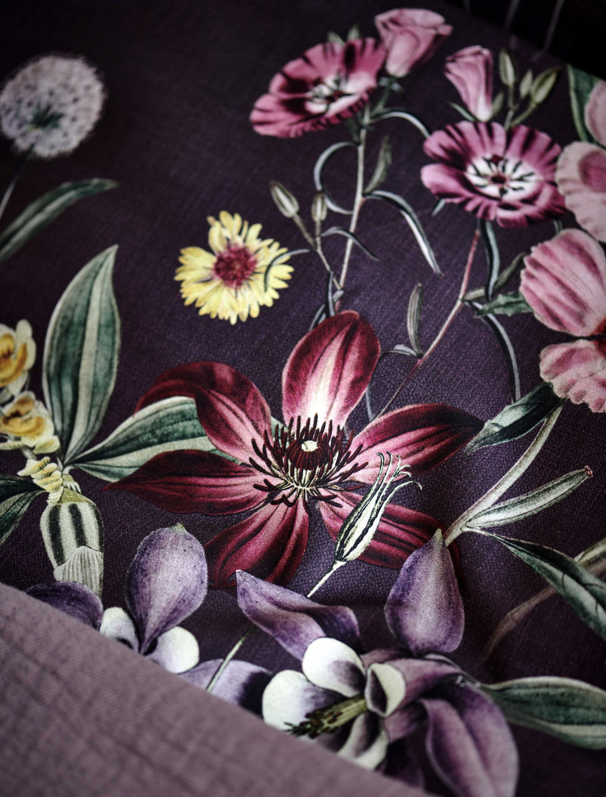 detail shot van een hoofdkussen in een paarse kleur met bloemen in rode en paarse kleuren