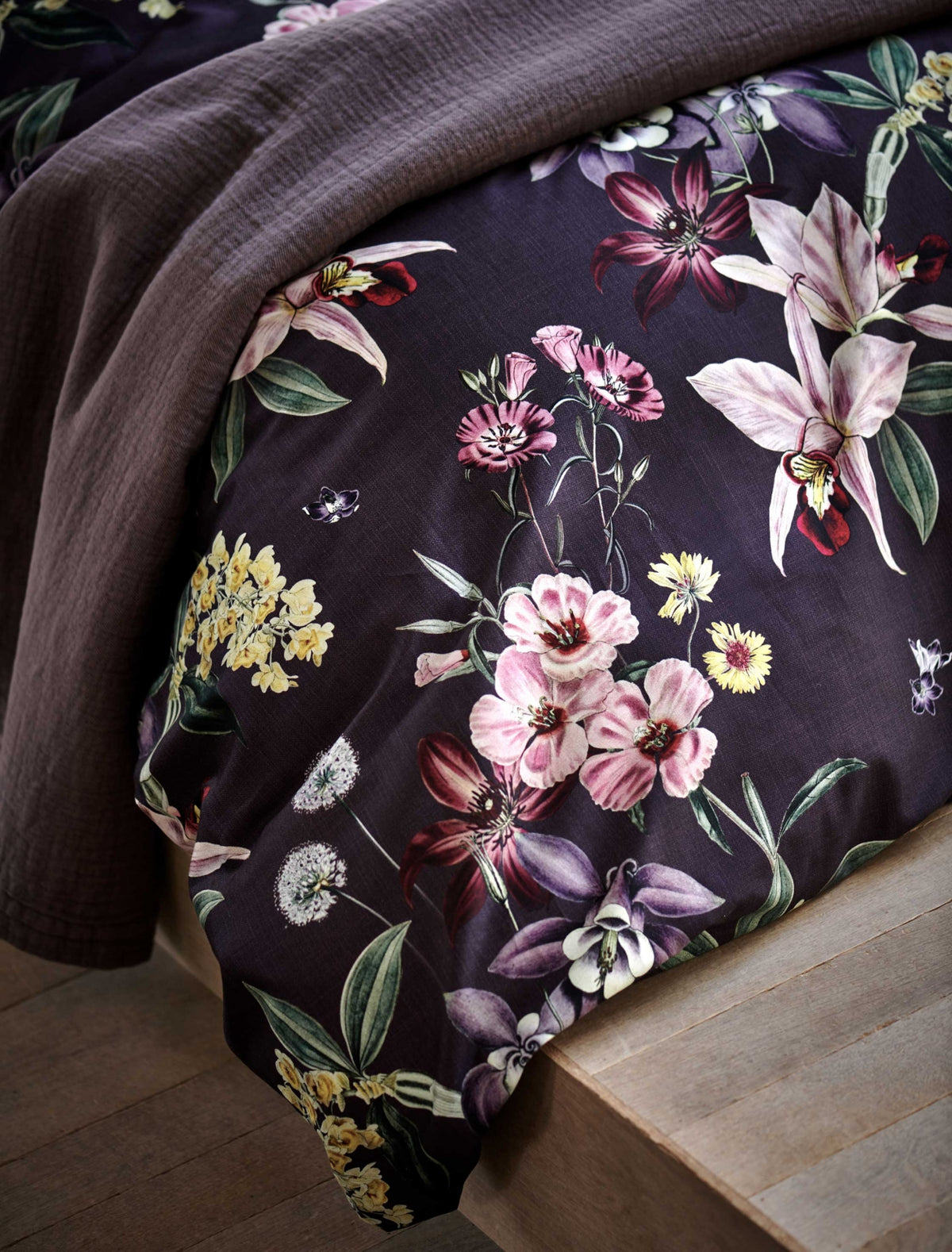 detail shot van een paars dekbedovertrek met bloemen in roze, rode en gele kleuren