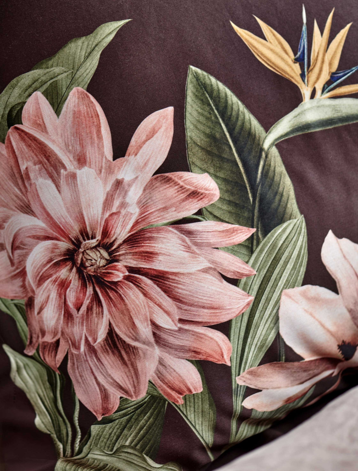 detail shot van een hoofdkussen in een bruine kleur met daarop een roze bloemenprint en een paradijsvogel