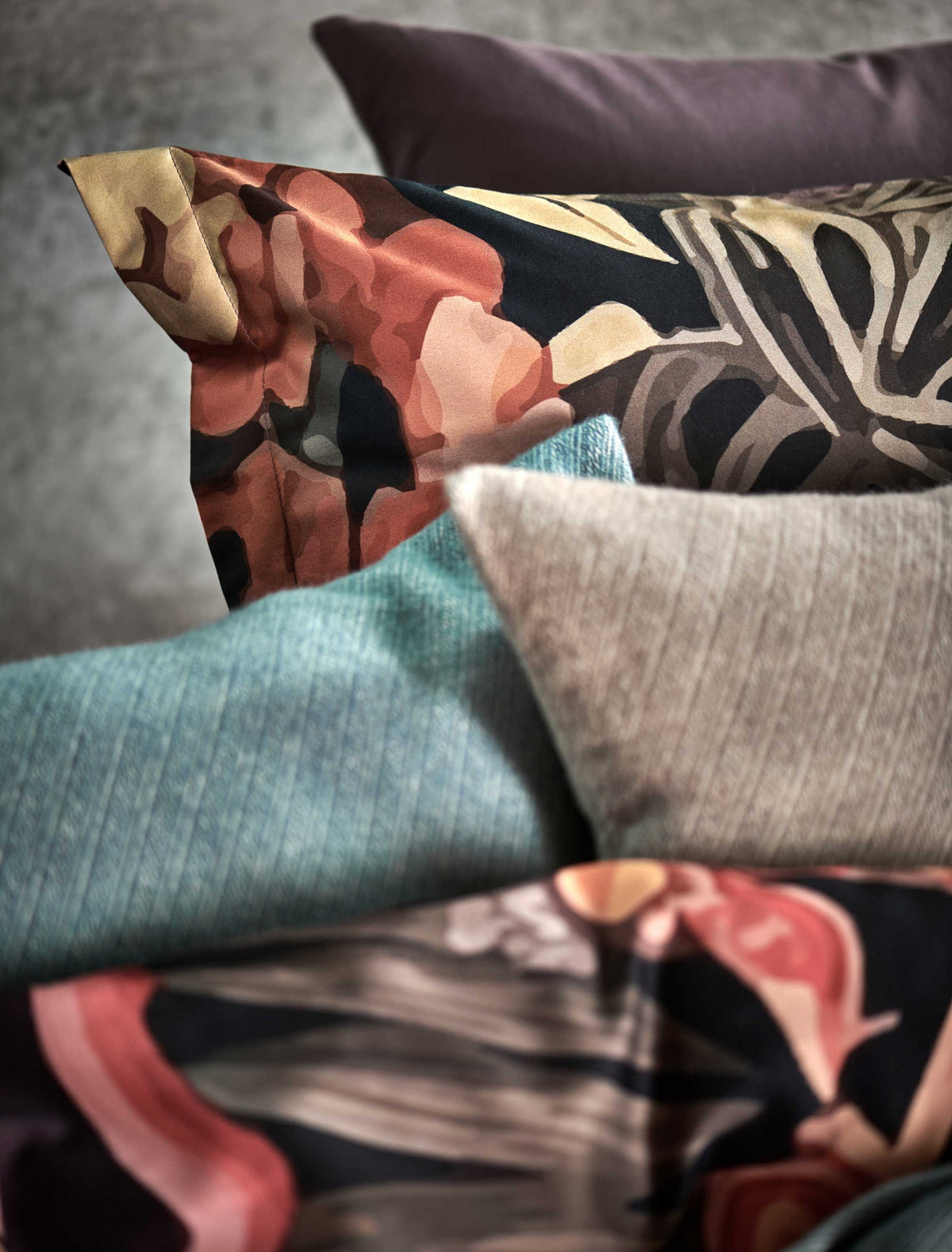 detail shot van een bed met een kussensloop met bloemen en sierkussens in de blauwe en bruine kleuren