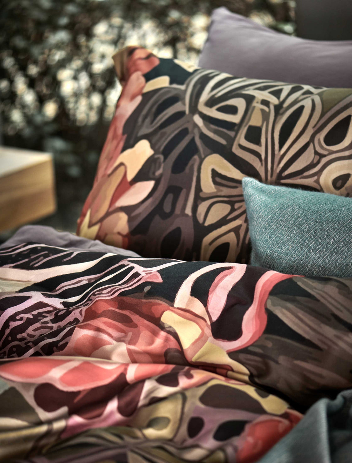 detail shot van een dekbedovertrek met een getekende print van bloemen en bladeren in paarse, roze en oranje kleuren