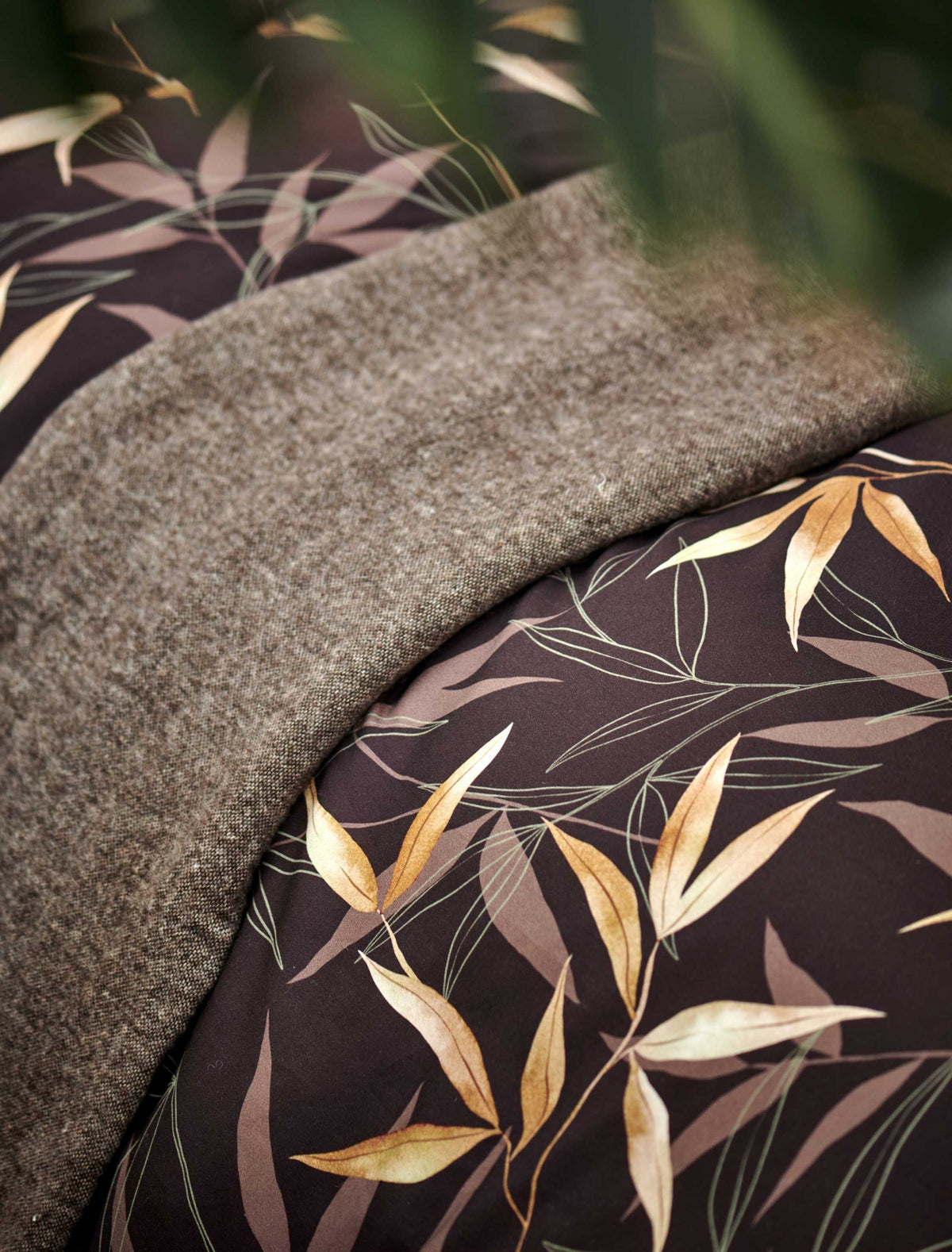 detail shot van een bruin dekbedovertrek met bamboe takken en een bruin plaid
