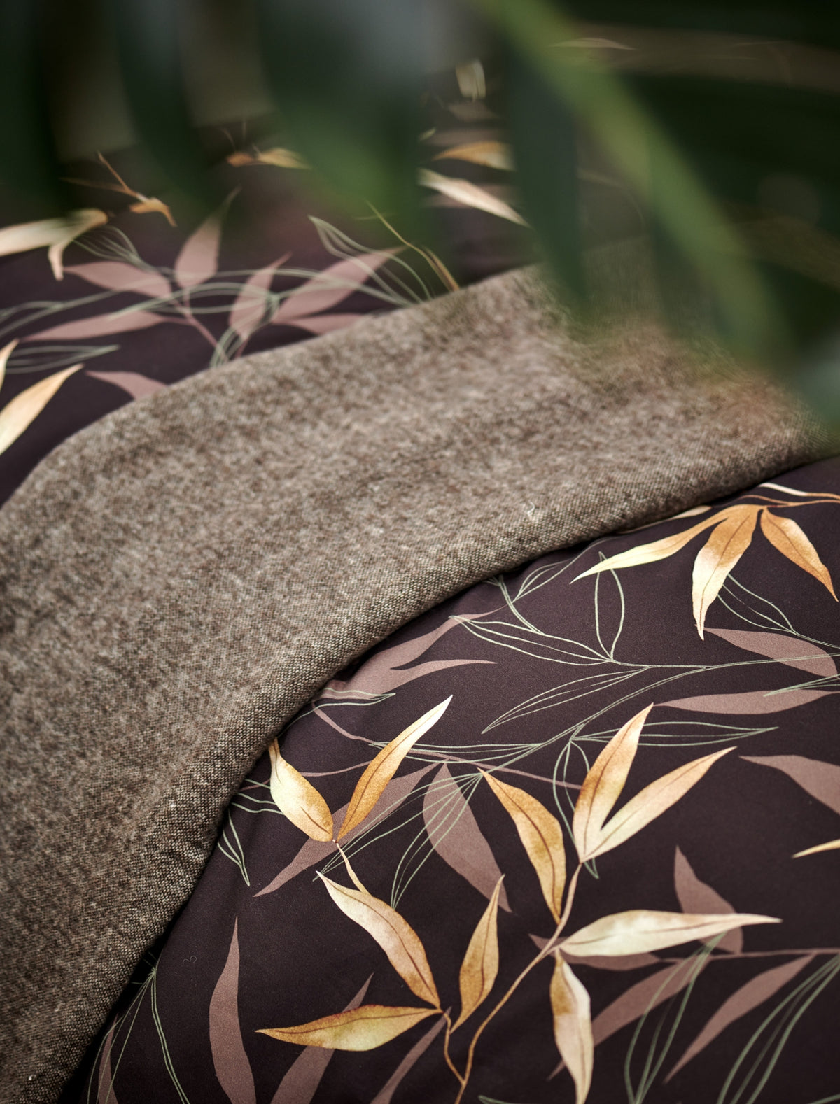 detail shot van een plaid en een dekbedovertrek in bruin met bamboe takken