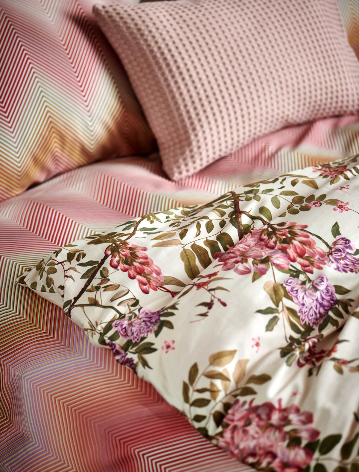 detail shot van een dekbedovertrek met roze en paarse bloemen en een dekbedovertrek met zigzag print in roze en oranje kleuren
